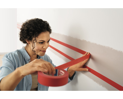 Femme collant du ruban de masquage sur un mur