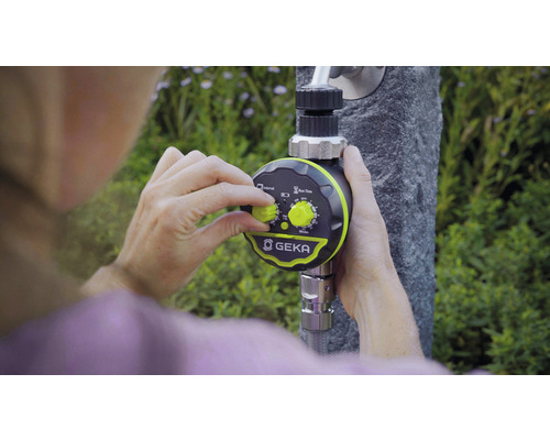 Une personne règle la commande d''arrosage GEKA fixée à un robinet.