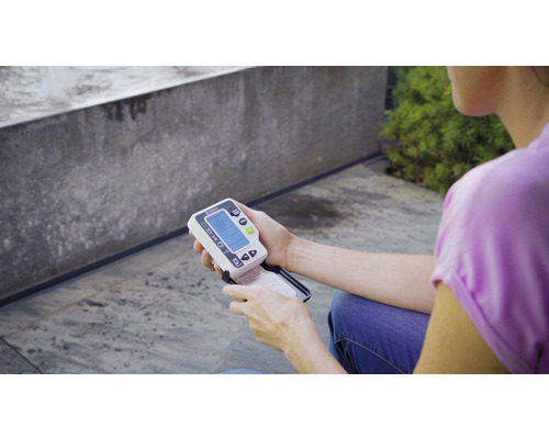 Une personne tient un humidimètre de sol Gardena dans sa main