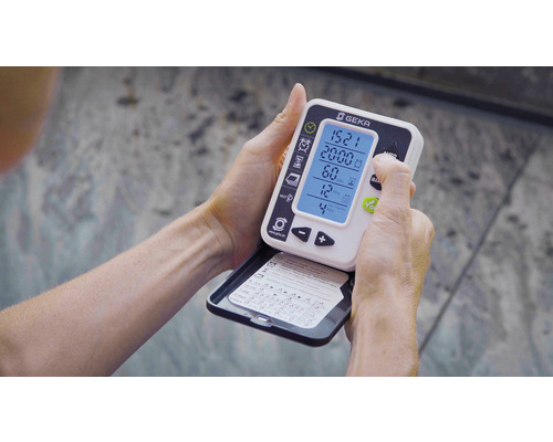 Une personne tient un programmateur d''arrosage Geka dans ses mains et l''utilise.