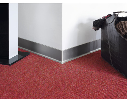 Plinthe murale en métal sur un mur blanc et un sol en moquette rouge