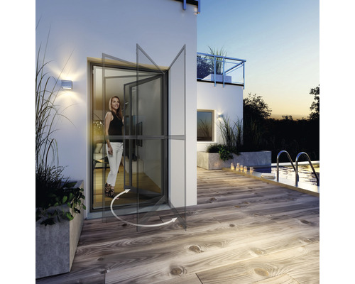 Porte battante avec protection contre les insectes en position ouverte devant une façade de maison