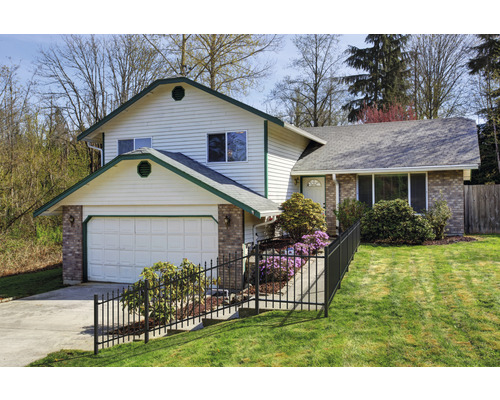 Vue d''une maison à deux étages avec garage, clôture et pelouse soignée