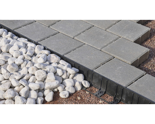 Pose de pavés gris avec bordure et pierres blanches décoratives.