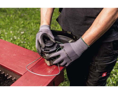 Personne changeant la tête de fil d''un coupe-bordures