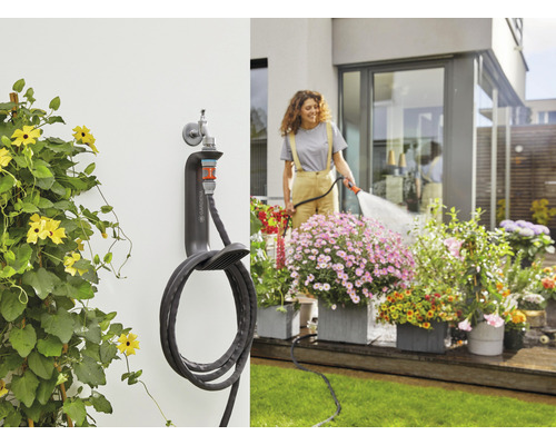 Gartenszene mit Wand-Schlauchbox und Frau, die Blumen giesst