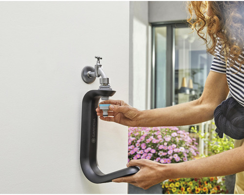 Gardena Wasserhahn-Anschluss mit Person beim Anschliessen eines Schlauchstücks an einen Wasserhahn