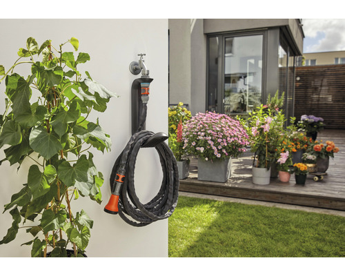 Gartenszene mit Schlauchwagen und Gartenschlauch an einer Hauswand