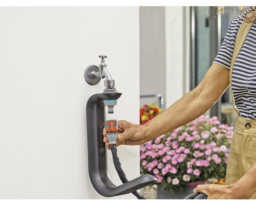Gartenszene mit Wasserhahn, Schlauchverbinder und Schlauchhalterung zur Bewässerung