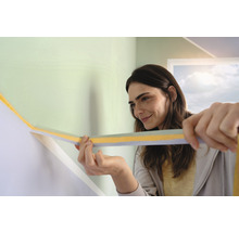 Frau bringt Abdeckband auf einer Wand an