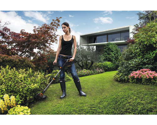 Une femme utilise un coupe-bordure Worx dans un jardin