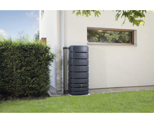 Regenwassertank aus Kunststoff mit Anschluss an ein Fallrohr vor einer Hauswand