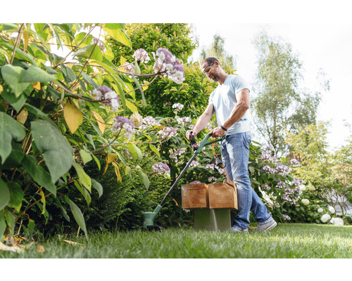Homme coupant du gazon avec un coupe-bordure dans un jardin