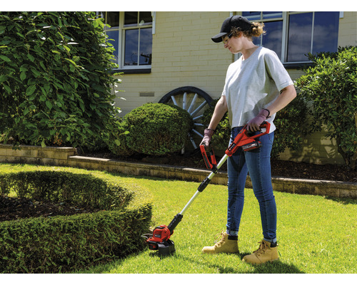 Femme utilisant un coupe-bordures à batterie dans le jardin.