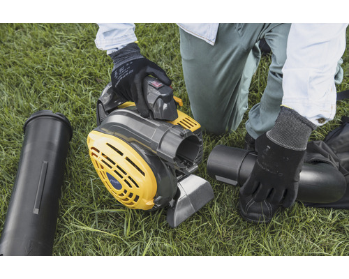 Une personne assemble un aspirateur de feuilles mortes jaune-gris sur une pelouse.