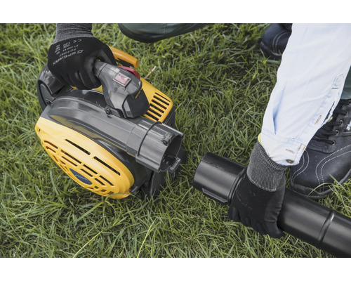 Un aspirateur à feuilles jaune est monté sur une pelouse.