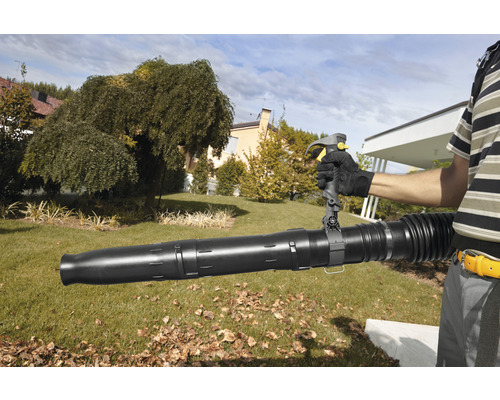 Une personne utilise un souffleur de feuilles dans le jardin.