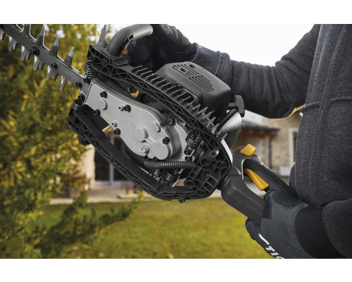 Une personne utilise un taille-haie pour tailler le jardin.