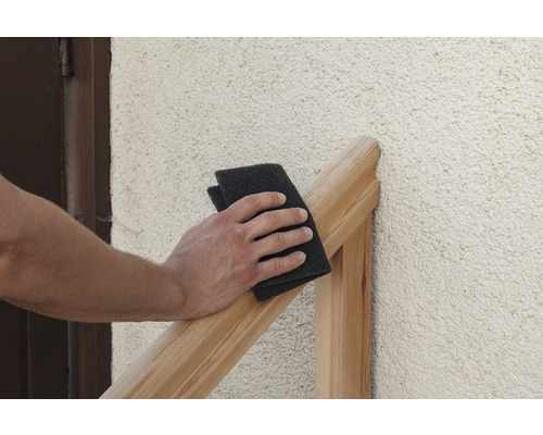 Une personne ponce une pièce de bois avec un tampon à poncer.