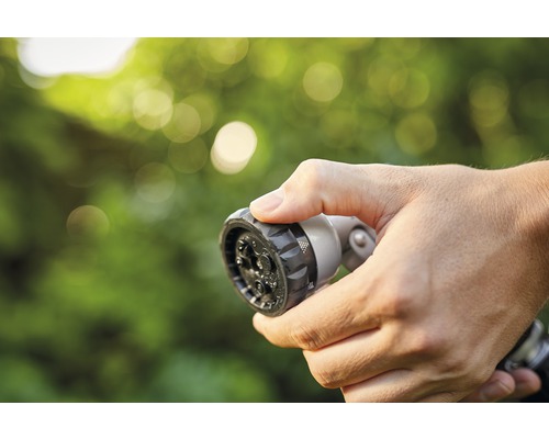 Hand hält Gartenschlauch-Sprühkopf