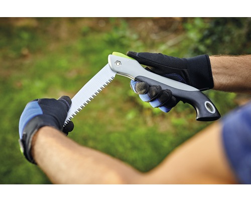 Une personne tient une scie pliante avec des gants.