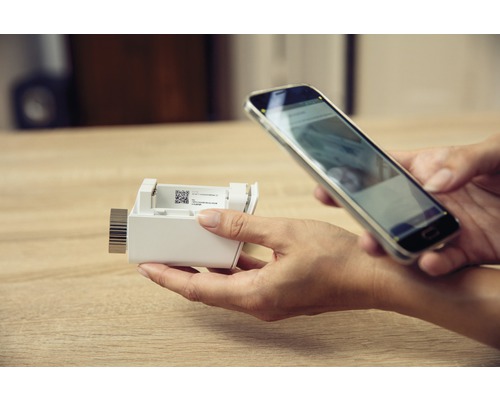 Une personne scanne une serrure de porte électronique avec un smartphone.