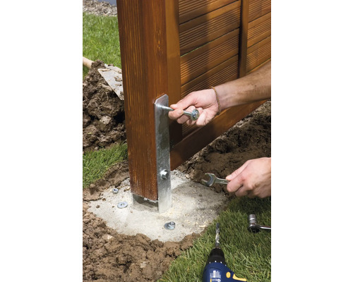Montage eines Zaunpfostens mit einer Bodenhülse im Garten