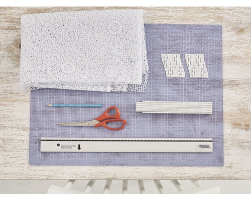 Matériel de bricolage comprenant du tissu, des ciseaux, un crayon, une règle et un tapis de découpe