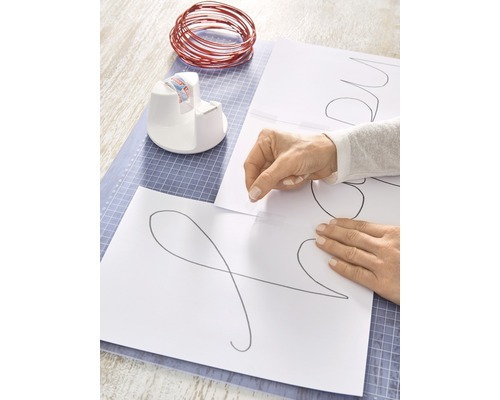 Bastelanordnung mit Draht, Vorlagen, Klebebandabroller und Schneideunterlage für DIY-Projekte.