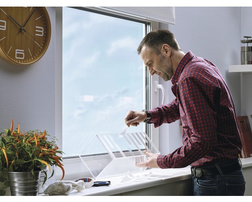 Ein Mann bringt Insektenschutzgitter an einem Fenster an.