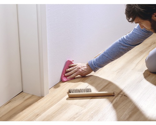 Homme nettoie les plinthes avec un chiffon et une brosse