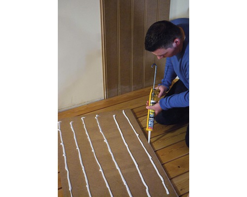 Un artisan applique de la colle sur une plaque de bois à l''aide d''un pistolet à cartouche