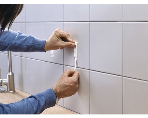 Personne fixant un système de nivellement de carreaux sur un mur carrelé