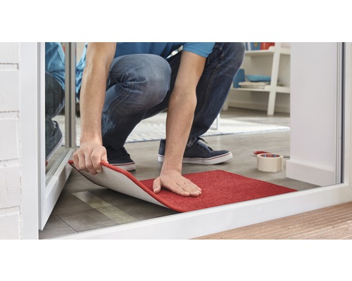 Un homme pose un tapis rouge dans la pièce.