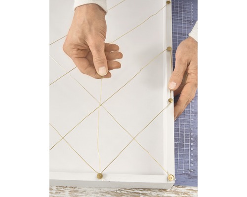 Une personne crée une décoration murale avec de la ficelle et des clous