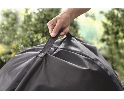 Une personne tient un sac de jardin noir par la poignée