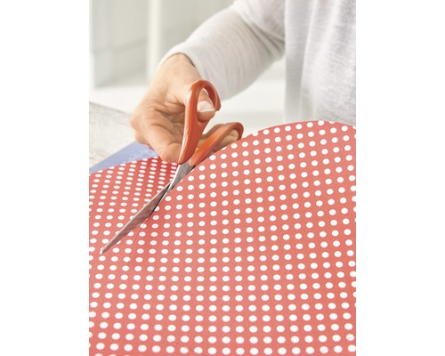 Personne coupant du papier à pois avec des ciseaux.