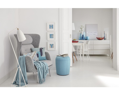 Séjour avec fauteuil, lampadaire et pouf dans une ambiance claire et conviviale.