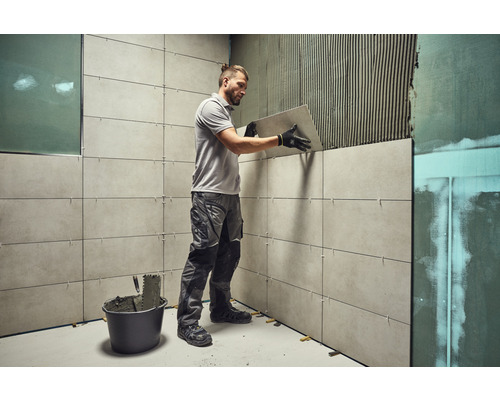 Ein Handwerker verlegt Wandfliesen im Badezimmer.