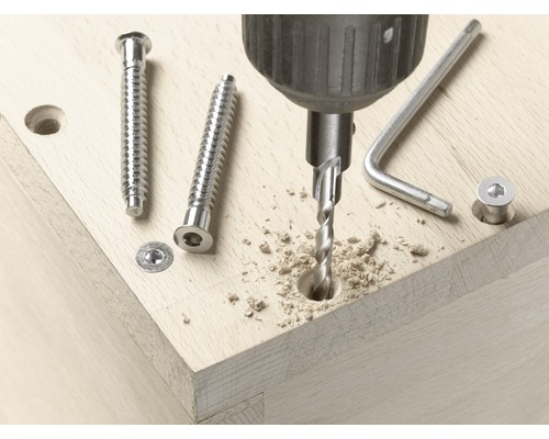 Perceuse perçant un trou dans du bois, vis et clé à pipe à portée de main