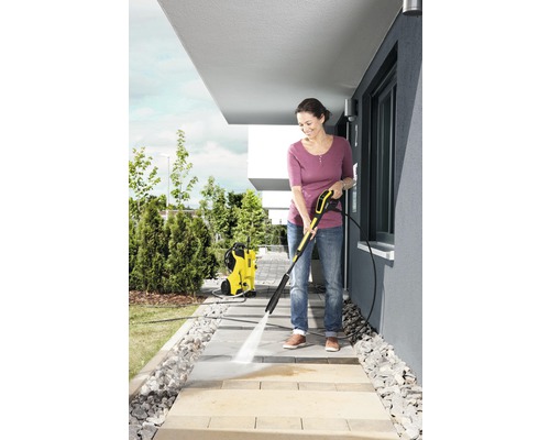 Une femme nettoie des dalles de trottoir avec un nettoyeur haute pression Kärcher.