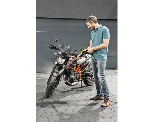 Un homme nettoie une moto avec un nettoyeur haute pression