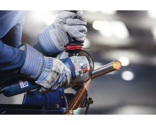 Personne meulant un tube métallique avec une meuleuse d''angle dans un étau