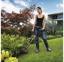 Femme utilisant un coupe-bordure dans le jardin.