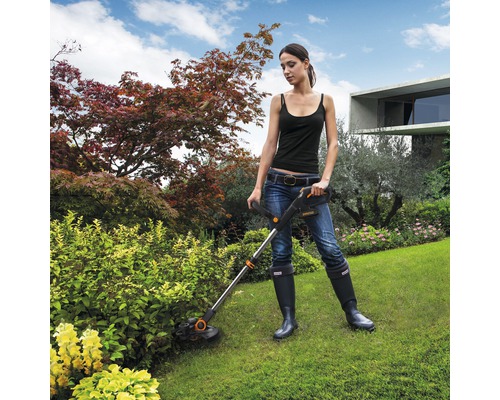 Une femme travaille avec un coupe-bordures dans le jardin.