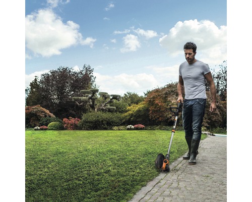 Un homme utilise un coupe-bordures dans le jardin pour tailler les bordures de la pelouse.