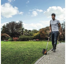 Un homme utilise un coupe-bordure sur une pelouse bien entretenue.