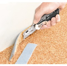 Une main coupe un tapis avec un couteau universel
