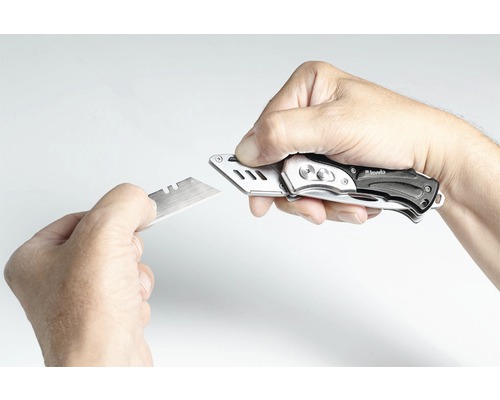 Eine Hand wechselt die Klinge eines Cuttermessers