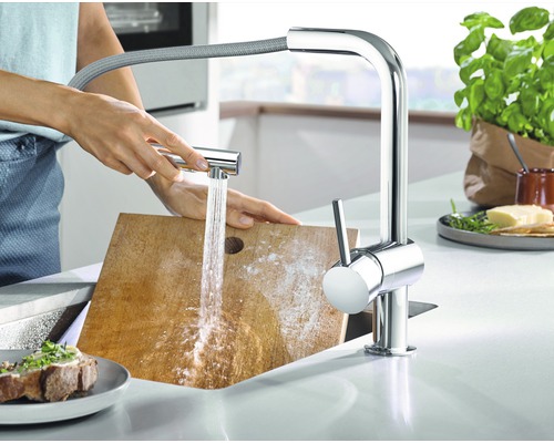Scène de cuisine avec robinet, jet d''eau et personne nettoyant une planche à découper
